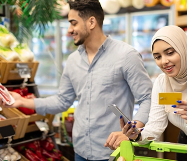 A couple shopping for groceries using a card in the supermarket

