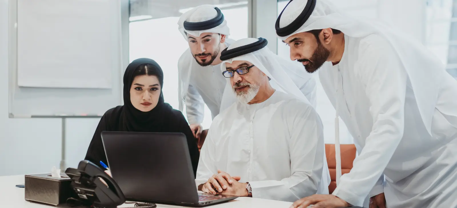 business team collaborating around laptop in modern office meeting room