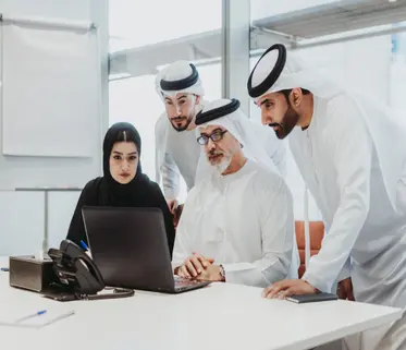 business team collaborating around laptop in modern office meeting room