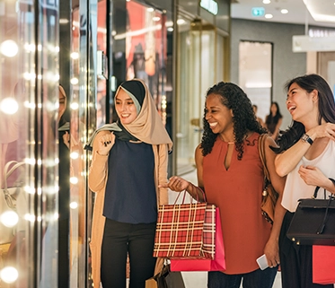Three women are shopping together and looking at the store display

