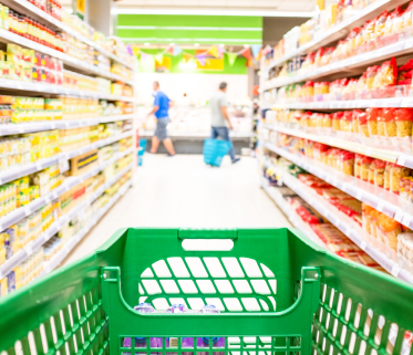 POV shot of green shopping cart in supermarket aisle with shelves of products