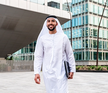 Emirati businessman walking outside modern office building

